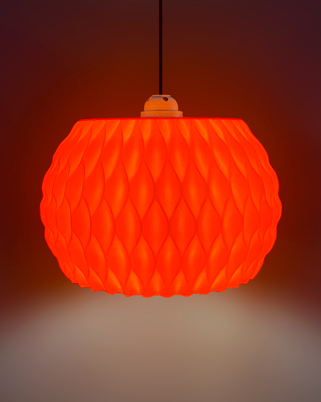 An orange textured pendant light with a honeycomb-like pattern, suspended by a black cord against a dark gradient background.